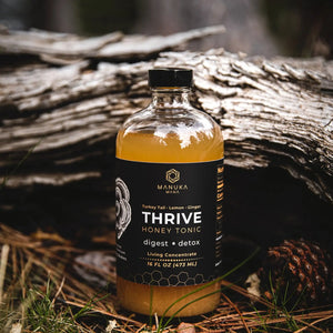 A bottle of Manuka Mana's turkey tail tonic is pictured in nature in front of a log.