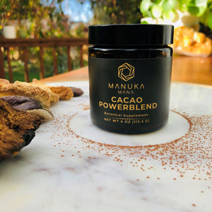 Jar of Cacao Powerblend on white table dusted with cacao powder. 