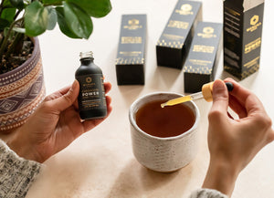 The Manuka Mana Cordyceps tincture is pictured with a dropper full of it being dropped into a tea cup.