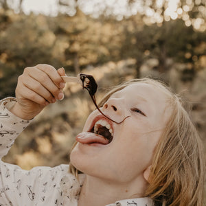 A boy is eating a spoonful of the Cacao Powerblend in nature to demonstrate one of the two products in the energy bundle. 