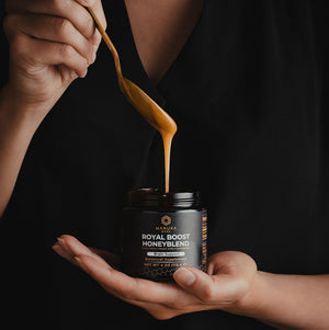 A spoon is shown drizzling the Royal Boost Honeyblend back into a jar. 