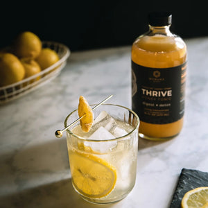 A glass bottle of Manuka Mana's turkey tail tonic is pictured next to a drinking glass of the tonic with ice.  