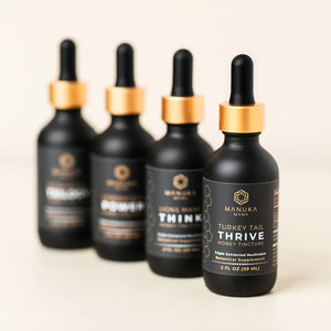 Manuka Mana's tincture bundle is pictured with all four tincture bottles lined up in a row, including turkey tail, lion's mane, cordyceps, and mushroom trilogy tinctures.